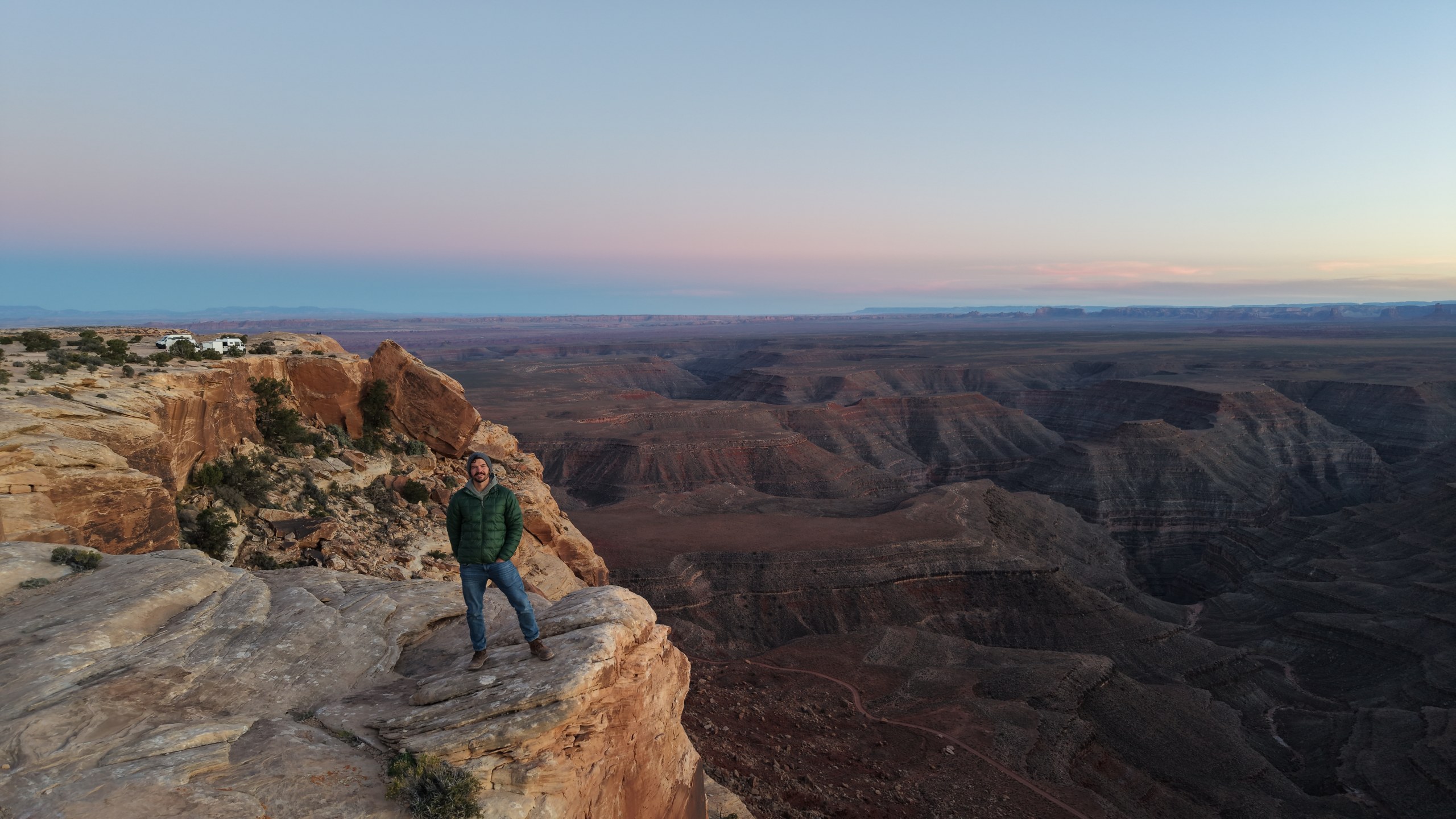Taylor standing on a sandstone cliff above a wide canyon at dusk