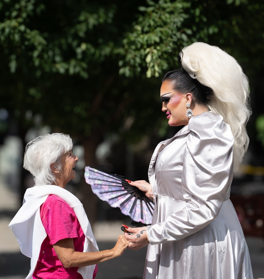 A Pride performer and an attendee holding hands and smiling