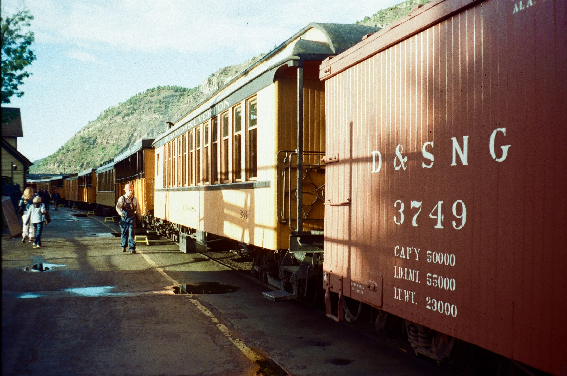 Red and yellow Durango and Silverton train cars in afternoon light